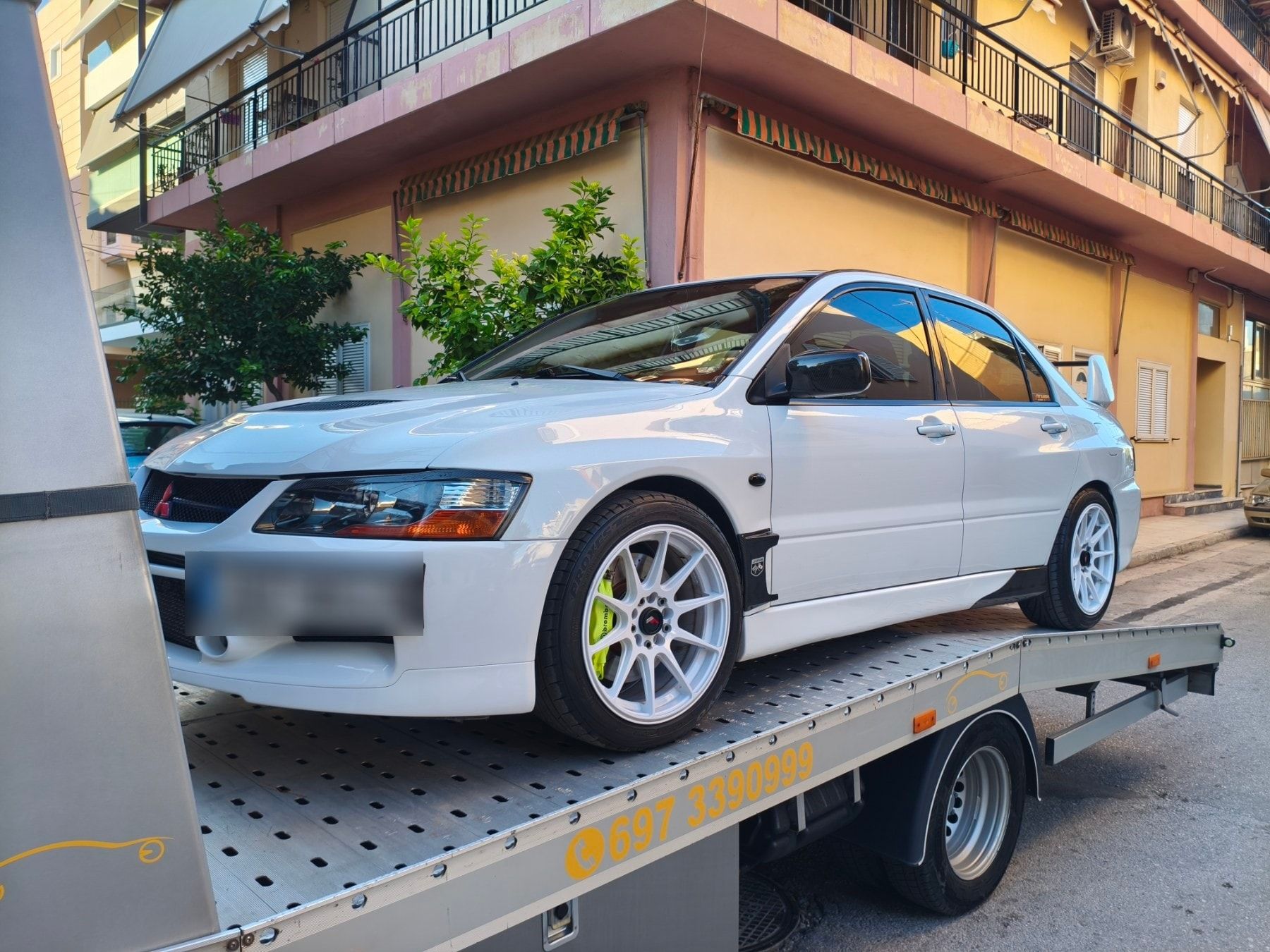 Λευκό Mitsubishi Lancer Evolution φορτωμένο στην πλατφόρμα της Instant Assistance σε δρόμο της Αθήνας