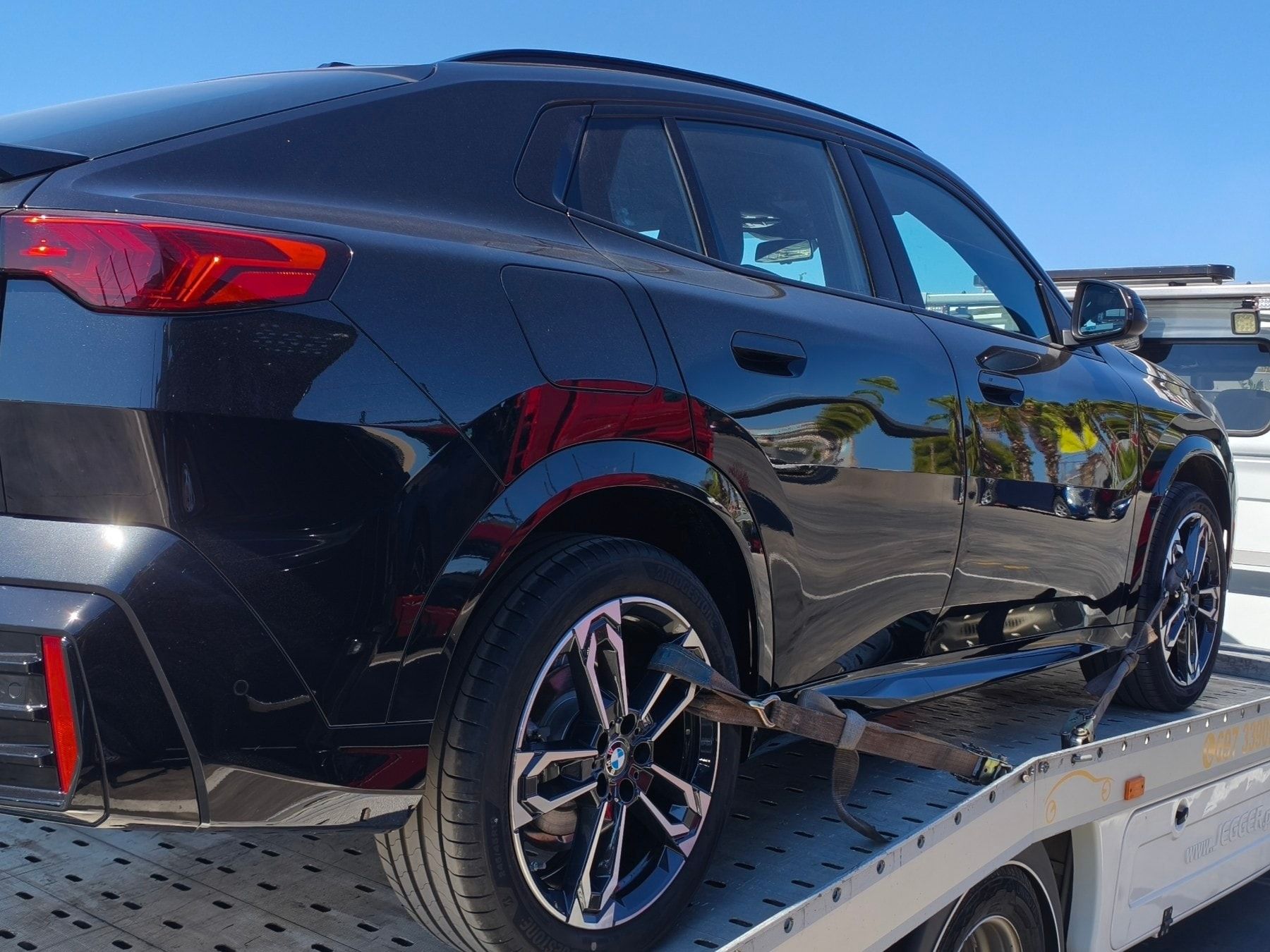 Μαύρο BMW X2 ασφαλισμένο με ιμάντες τροχών στην πλατφόρμα